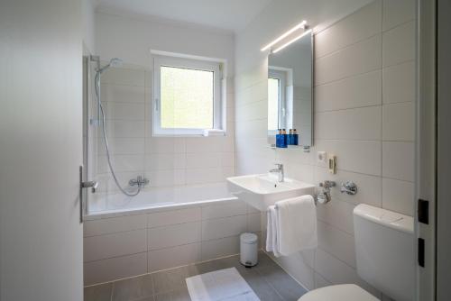 a white bathroom with a sink and a bath tub at Blue Sky Apart Center Baden-Baden in Baden-Baden
