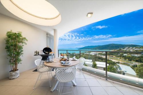 Un comedor con mesa y sillas en un balcón. en Pacific Blue - Premiere, en Airlie Beach