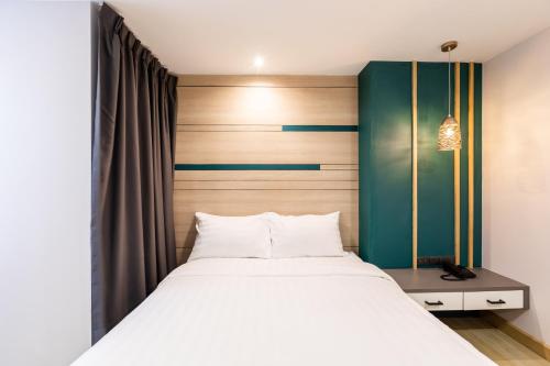 a bedroom with a white bed and a green headboard at City Park Hotel Bangkok Pratunam by PCL in Bangkok