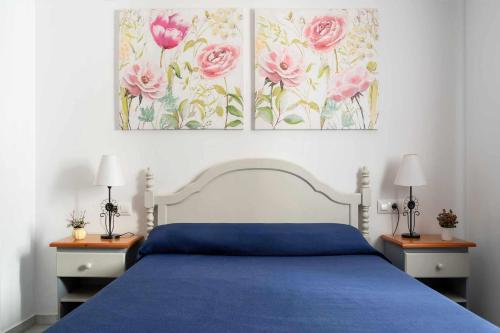 una camera da letto con un letto blu con rose rosa sul muro di Piso Saturno 1ºD Conil Alquileres Atardecer a Conil de la Frontera