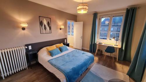 Schlafzimmer mit einem Bett mit blauer Bettwäsche und einem Fenster in der Unterkunft Hotel De La Poste in Mortain