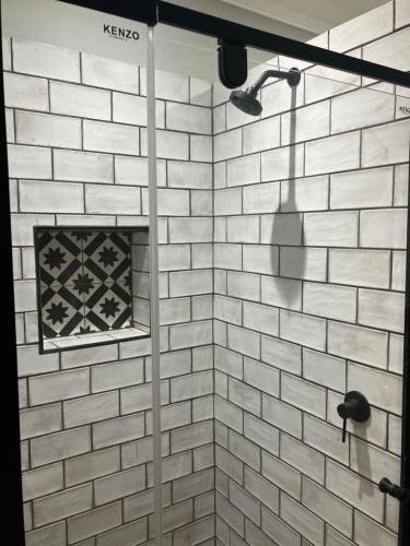 a bathroom with a shower with a white brick wall at UpperRoom Ceres -Indoor Braai in Ceres