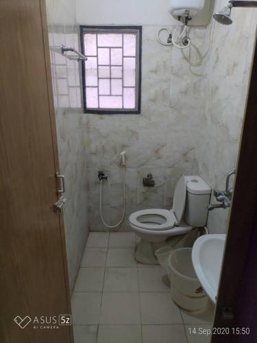 a bathroom with a toilet and a sink and a window at GT Service apartments in Chennai