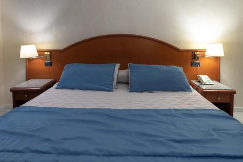 a blue bed with two blue pillows and a phone at Edra Palace Hotel & Ristorante in Cassino