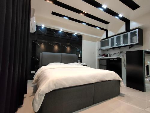 a bedroom with a large bed and a kitchen at Burgundy McKinley Place Service Apartment in Manila