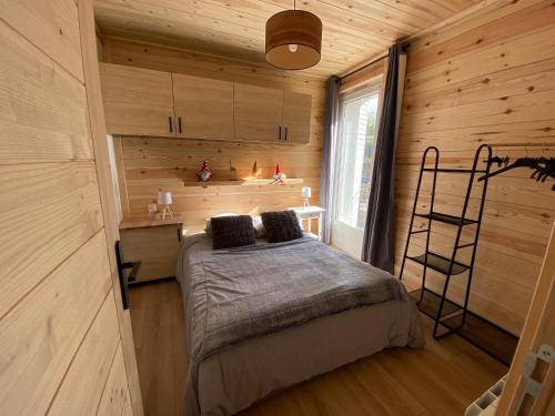 a bedroom with a bed in a wooden cabin at Charmant T2 en plein centre de Formiguères in Formiguères