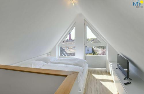ein weißes Schlafzimmer mit einem Bett und einem Fenster in der Unterkunft Haus am Dorfbrunnen Ferienwohnung Düne in Wangerooge