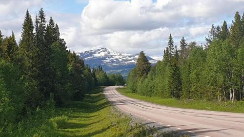 a road with a snow covered mountain in the distance at Mountain Holiday Homes - Ottsjö, Trillevallen -Sweden in Åre
