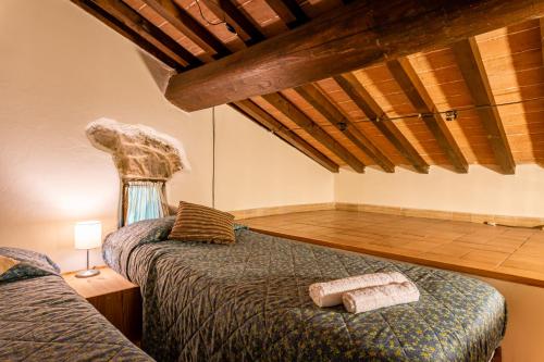two beds in a room with wooden ceilings at Il Colletto Romantic Stonehouse in Pescia