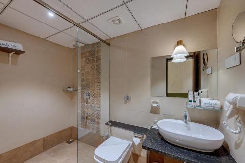 a bathroom with a sink and a shower and a toilet at Guruprerna Beacon Resort, Dwarka in Dwarka