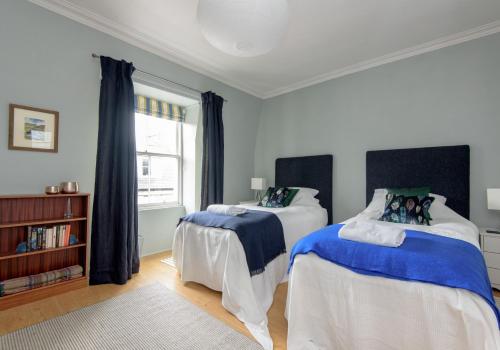 a bedroom with two beds with blue and white sheets at Rooftops in North Berwick