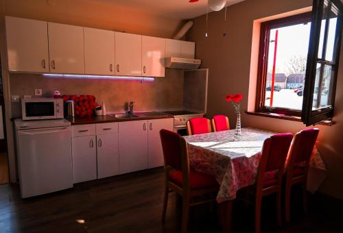 una cocina con mesa con sillas rojas y una cocina con armarios blancos en Mad House Apartment 2, Terme Čatež, en Brežice
