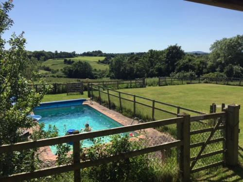 a swimming pool in a yard next to a fence at The Dragon's Hut with cozy logburner in Wrexham