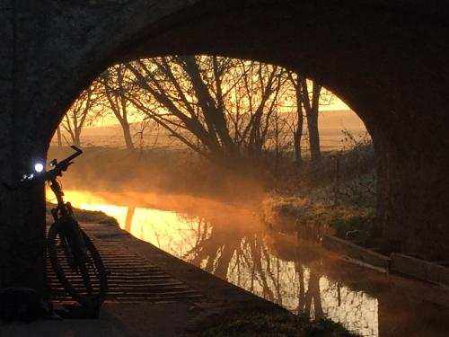 a bike parked under a bridge next to a river at The Dragon's Hut with cozy logburner in Wrexham