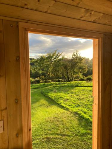 a window view of a field through a wooden door at The Dragon's Hut with cozy logburner in Wrexham