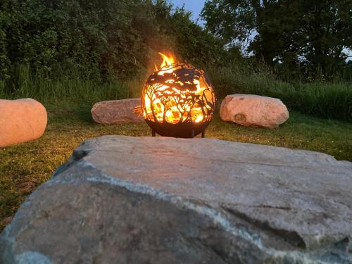 a fire pit in a yard with rocks at The Dragon's Hut with cozy logburner in Wrexham