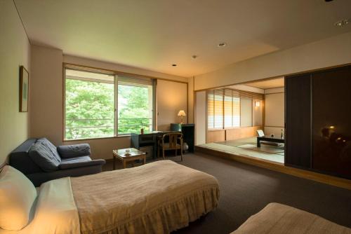 a bedroom with a bed and a chair and a window at Takamiya Hotel Lucent in Zao Onsen