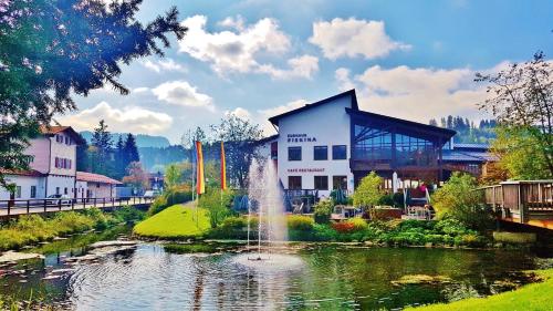 a building with a fountain in the middle of a pond at Ferienwohnungen Keiß in Fischen