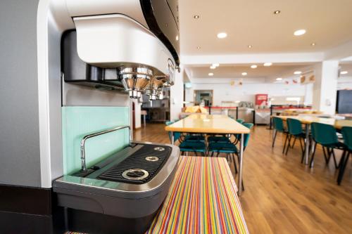 a kitchen with a stove and some tables and chairs at Albergue Inturjoven Sierra Nevada in Sierra Nevada