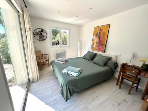 a bedroom with a bed with a green comforter at Villa Caprier in Le Pradet