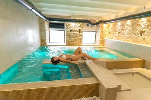 a woman laying on the edge of a swimming pool at Spa & Wellness by Des Anglais " Accesso SPA compreso" in Sanremo