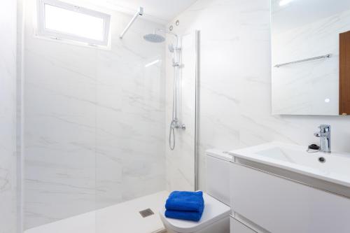 ein weißes Bad mit einem WC und einem Waschbecken in der Unterkunft Home2Book Duplex El Medano Pool & Terrace in El Médano