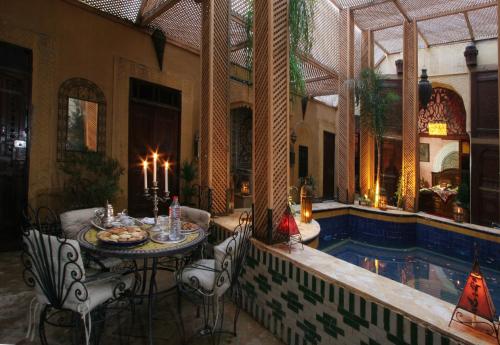 Palais Al Firdaous في فاس: غرفة مع طاولة وكراسي بجوار حمام سباحة