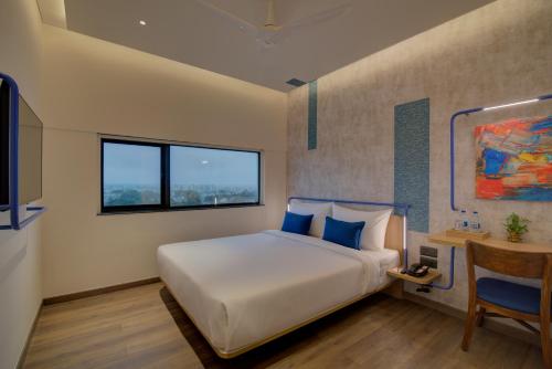 um quarto com uma cama, uma secretária e uma janela em 7 Apple Hotel Nashik em Nashik