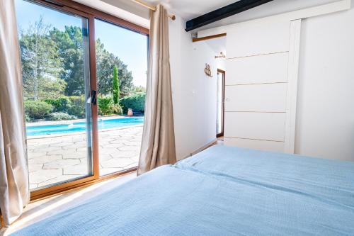 um quarto com uma cama e uma grande janela em La Piscine em Suze-la-Rousse