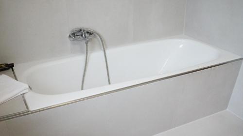 a white bath tub with a faucet in a bathroom at Hotel Specht by Trotmannia in Dortmund