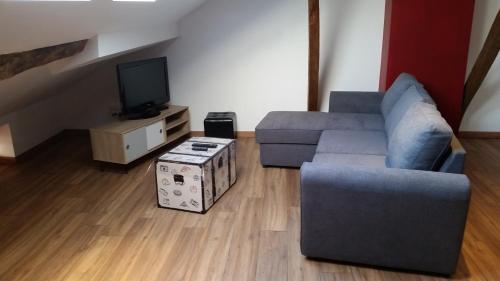 a living room with a couch and a tv at Logis Hôtel - Les Pasteliers in Lavaur