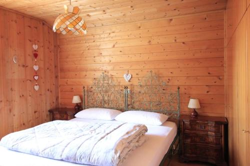 - une chambre avec un lit et un mur en bois dans l'établissement CASA PAMPEAGO - Sulle piste da sci del Latemar, à Tesero