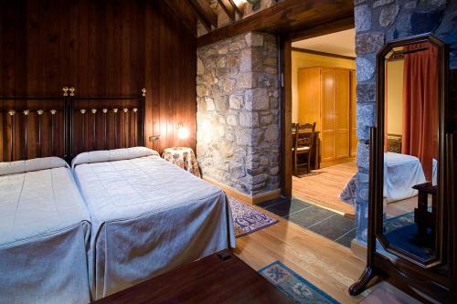 a bedroom with two beds and a stone wall at Hotel Hospital de Benasque in Benasque