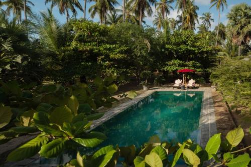 a swimming pool in a resort with two people sitting under an umbrella at Luna Laguna in Kalpitiya