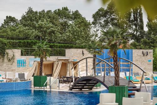 a resort pool with a slide and palm trees at A Hoteli - Hotel Izvor in Arandjelovac
