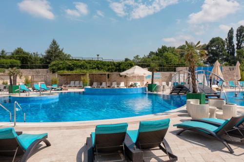 a large swimming pool with blue water and chairs at A Hoteli - Hotel Izvor in Arandjelovac
