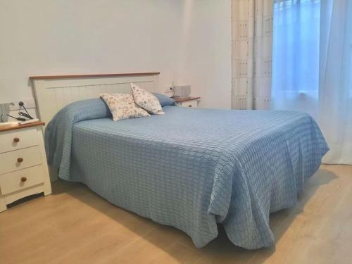 a bed with a blue comforter and two pillows on it at El rincón de Manolita. #2 in Bornos