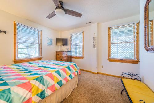 a bedroom with a colorful bed and windows at Sound Waves in Duck