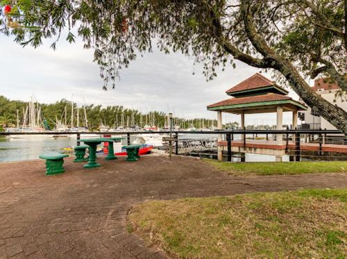 a group of green picnic tables next to a marina at Mzingazi Waterfront Accommodation, On The Bay Waterfront Villa's in Richards Bay