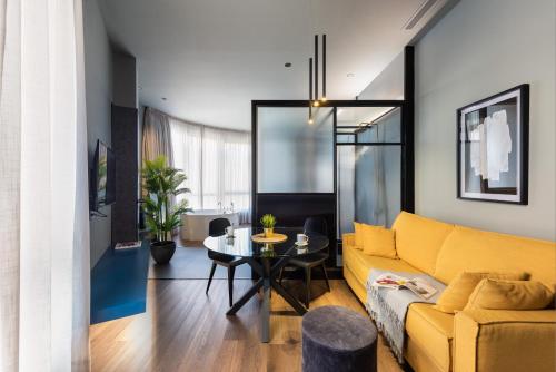 a living room with a yellow couch and a table at Muralla Sevilla Suites By Lola in Seville