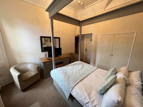a bedroom with a bed and a chair and a television at Broughton Craggs Hotel in Cockermouth