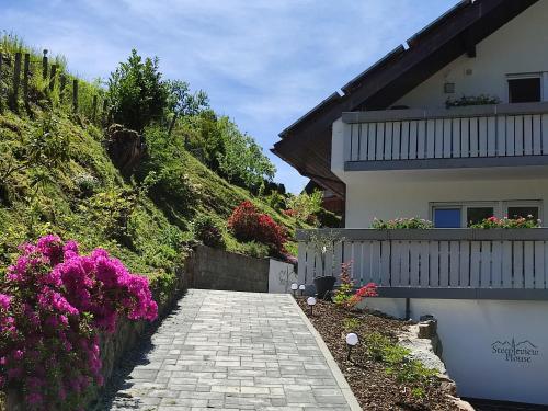 a stone walkway next to a house with flowers at Steepleview House, Schwarzwaldblick Apartment - spacious & peaceful in Bad Peterstal-Griesbach