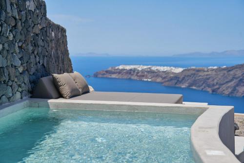 a pool with a bed and the ocean in the background at Divine Cave Experience in Imerovigli