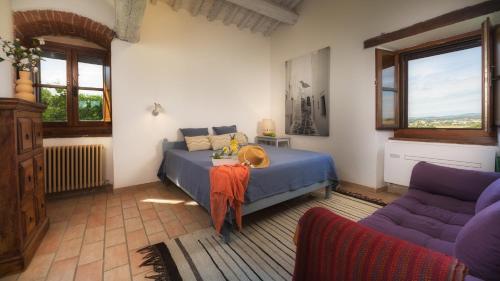 a bedroom with a bed and a couch and windows at LA VECCHIA PIEVE 8, Emma Villas in Castiglione della Valle