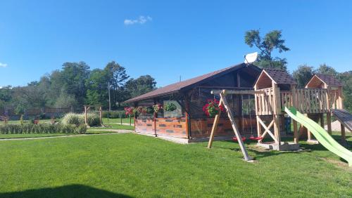 a playground in a park with a wooden building at Pensiunea Romosan in Cucuiş