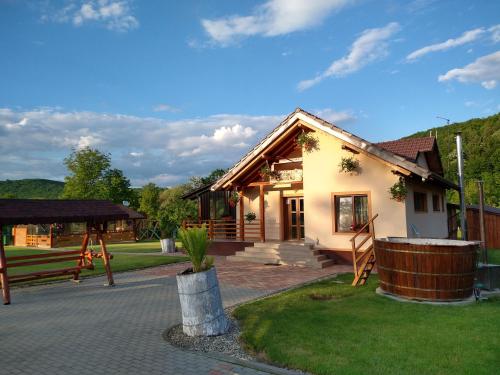 a small house with a porch and a playground at Pensiunea Romosan in Cucuiş