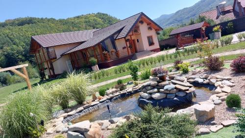 a home with a pond in front of a house at Pensiunea Romosan in Cucuiş