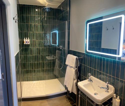 a green tiled bathroom with a sink and a shower at The Peat Spade Inn in Stockbridge