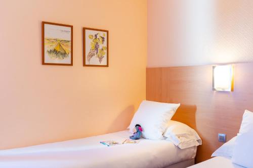a bedroom with two beds and a stuffed animal on a pillow at The Originals City, Hôtel Le Pavillon, Béziers Est in Béziers