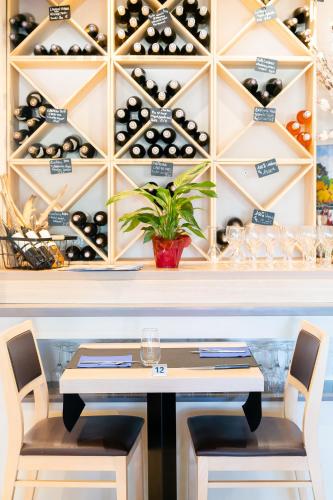 a dining room with a table and a wall of wine bottles at The Originals City, Hôtel Le Pavillon, Béziers Est in Béziers
